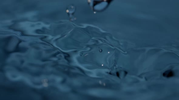 Continuous Water Dripping Creating Numerous Droplets on Blue Water in Closeup