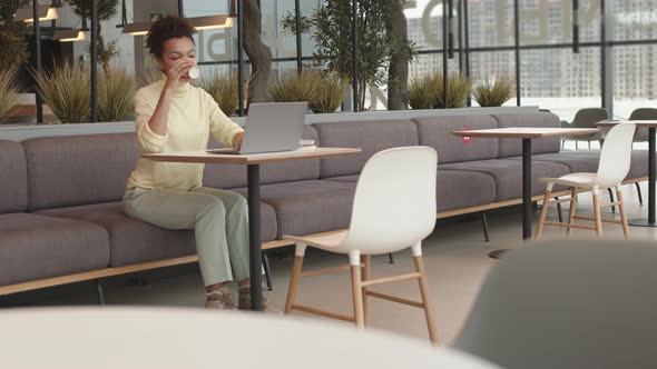 Mixed-Race Woman Drinking Coffee in Coworking