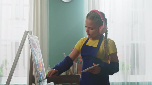 Small Girl In Wireless Headsets Is Painting