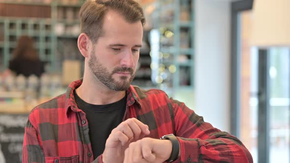 Portrait of Serious Young Man Using Smart Watch 