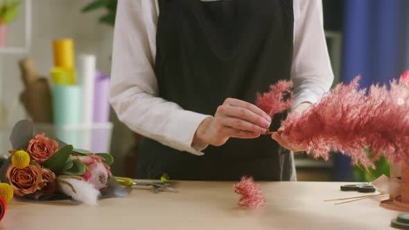 Young Florist Preparing Red Dried Flowers for Bouquet Closeup