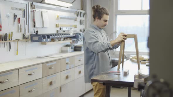 Young Carpenter Assembling Handmade Wooden Table at Workshop