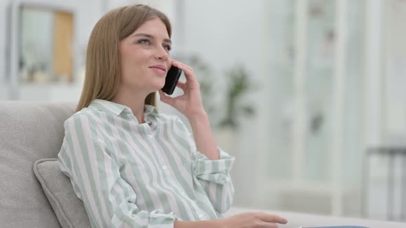 Cheerful Young Woman Talking on Smartphone at Home