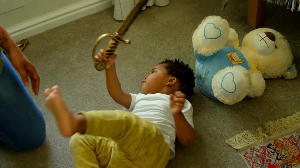 High angle view of cute little black boy playing and lying on floor of comfortable home 4k