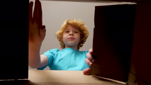 Blonde boy opens a package and is happy about the gift inside.