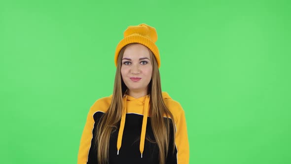 Portrait of Modern Girl in Yellow Hat Is Holding Back Laughter. Green Screen