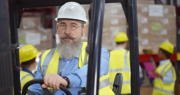 Happy Engineer Operating Forklift Truck in Warehouse