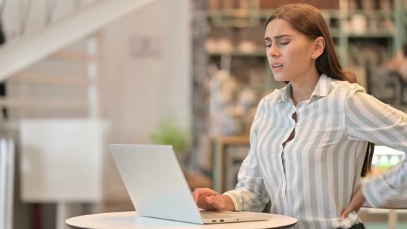 Tired Young Latin Woman with Laptop Having Back Pain in Cafe