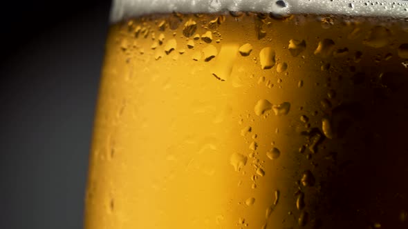 Craft Light Beer in Glass with Condensate and Water Drops. Rotating Over Dark Background