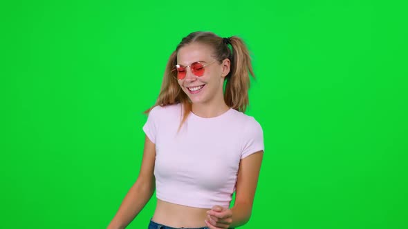 Caucasian Female Dances to the Music on a Green Background Cheerful Girl Takes a Video on for a