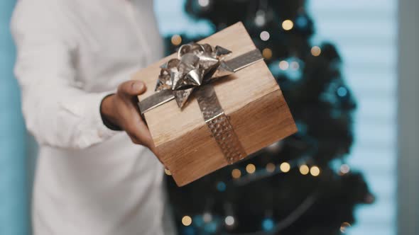 African American Black Man Giving Christmas Gift Gold Ribbon Front Christmas Tree