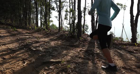 Fitness woman trail runner running on sunrise tropical forest mountain peak,slow motion