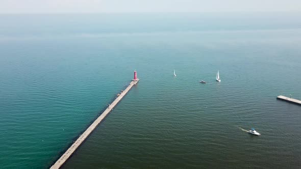 Aerial view of lake Michigan, drone flying around sailboats and lighthouse	