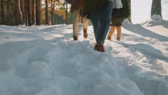 Unrecognizable Family Walking in Snow on Winter Day