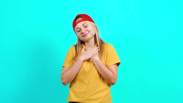 The Modest Young Woman Holds Her Hands To Her Chest, Gets Emotional and Shows a Heart with