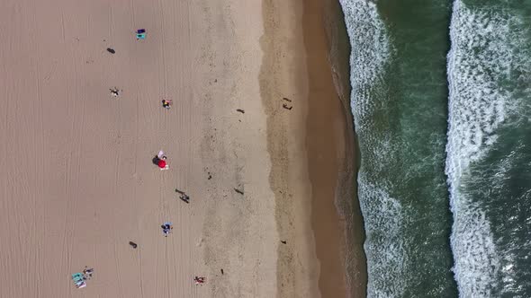 Top Down View Of Beach With Tourists On The Shore - aerial drone shot