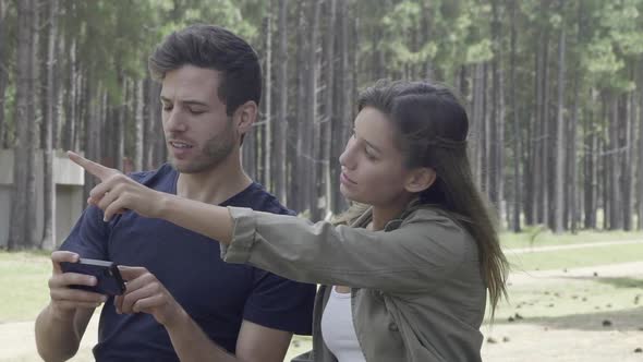 Couple using smart phone to navigate in woods