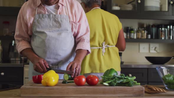 Senior mixed race couple wearing aprons preparing food in kitchen