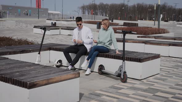 A Man and a Woman are Sitting on a Bench and Have a Conversation