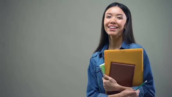 Asian Woman Standing With Copybooks on Grey Background