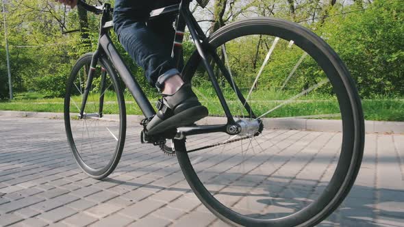 Tracking Shot of Hipster Man Riding Fixed Gear Bicycle in Park Slow Motion