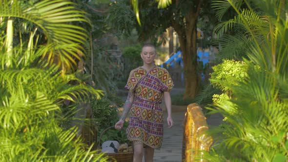 Medium shot of a female caucasian tourist walking through a tropical garden in summer