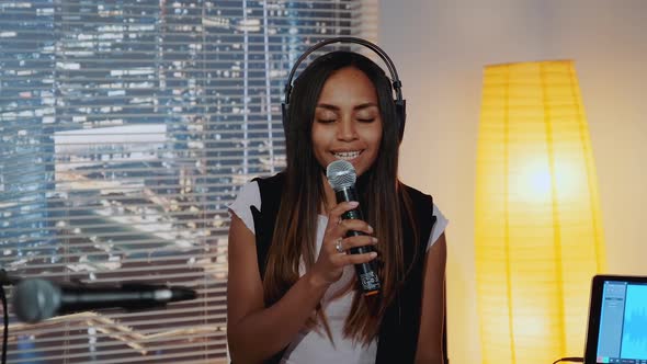 Closeup of Beautiful Multiracial Girl in Headphone Singing Into Microphone and Recording a Song in