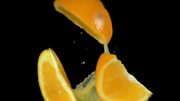 Wet Slices of Orange are Flying Up with the Splashes of the Orange Juice