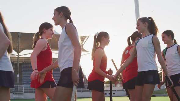 Female hockey players shaking hands each other on the field