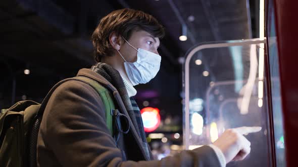 Young Man in Medical Mask Orders Bus Ticket Via Machine