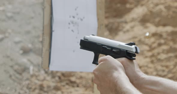 Close up footage of a hand gun firing in a firing range with cartridge flying away