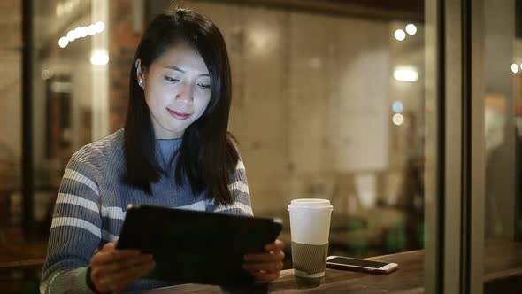 Woman using tablet pc at coffee shop at night