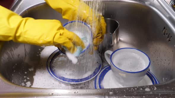 Hand Washing Dishes in Kitchen Sink