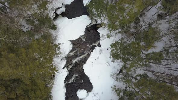 Top down drone shot of snowy river rapids in winter