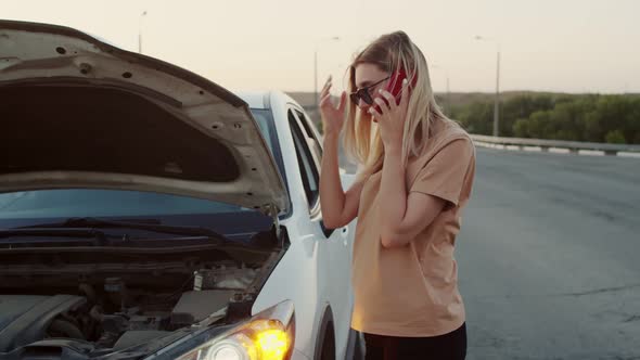 The Girl Is Standing with a Broken Car and Talking on the Phone. A Young Girl Is Standing at the Car