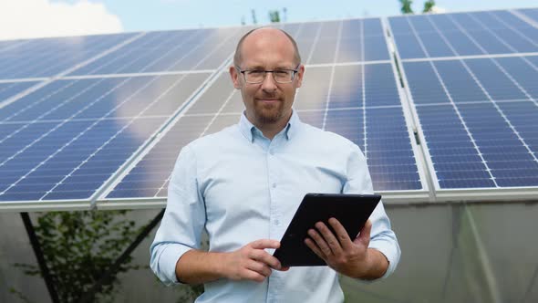 Close Up Portrait of Male Worker in Protective Helmet Standing Near Solar Panel