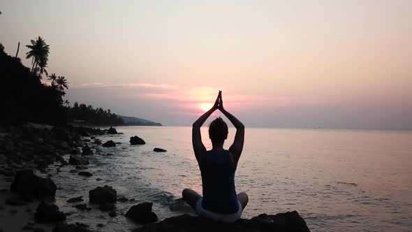 Silhouette of Woman By Practicing Yoga on Rocky Shore of Calm Sea on Sunset