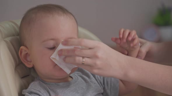 Mom wipes baby's face with a napkin after eating
