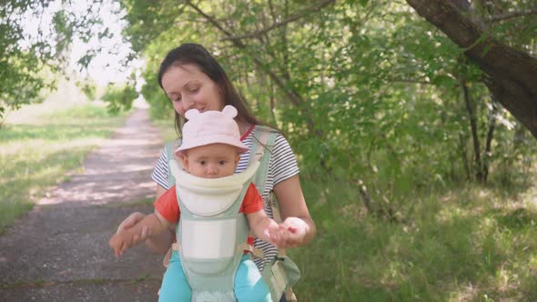 A mother with a newborn baby in a sling walk