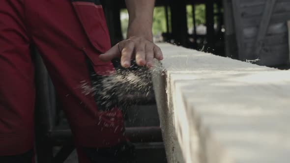 Hand Sweeps Sawdust From a Wooden Beam