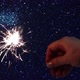 Hand Holds Sparkler on Blue Glittering Background - VideoHive Item for Sale