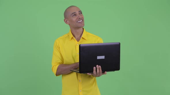 Happy Handsome Bald Businessman Thinking While Using Laptop