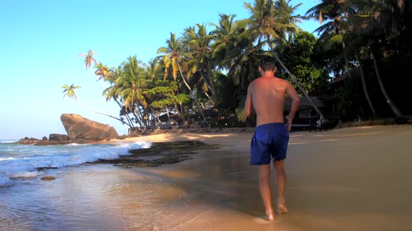 Barefoot Sportsman Runs Along Pictorial Ocean Coastline