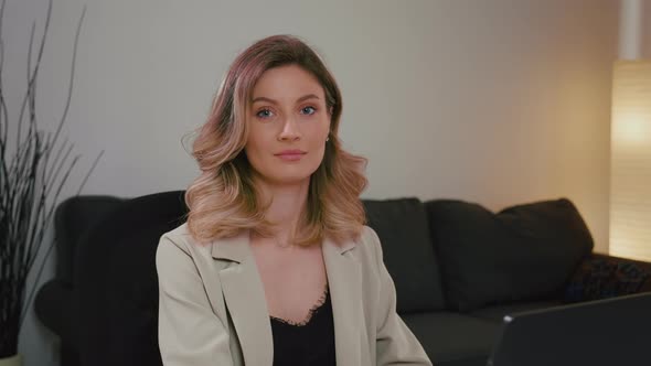 Business woman in gray suit working on laptop from home office.