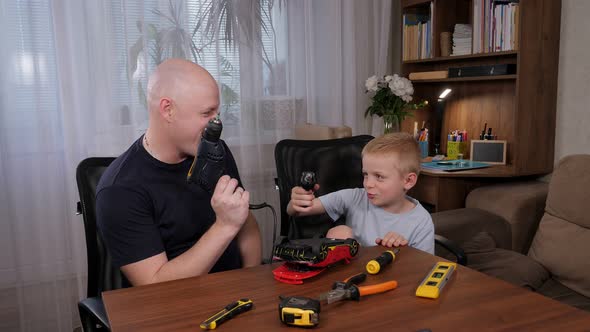 Cheerful Father and Son are Repairing a Toy Car with a Screwdriver