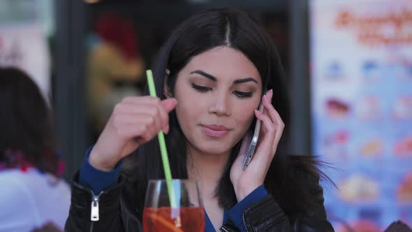 Beautiful young asian woman talking by smartphone and drinking at restaurant