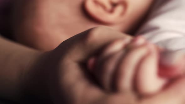 Baby Squeezes Mother's Hand with Small Fingers