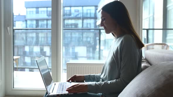 Happy Young Woman Using Laptop Computer for Video Connection From Home