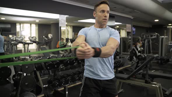 Man doing side-to-side chops exercise with elastic band at the gym.