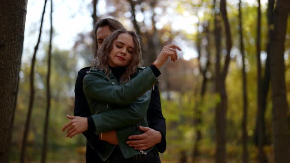 Pretty Woman is Dancing in Hugs of Her Beloved Man in Park in Autumn